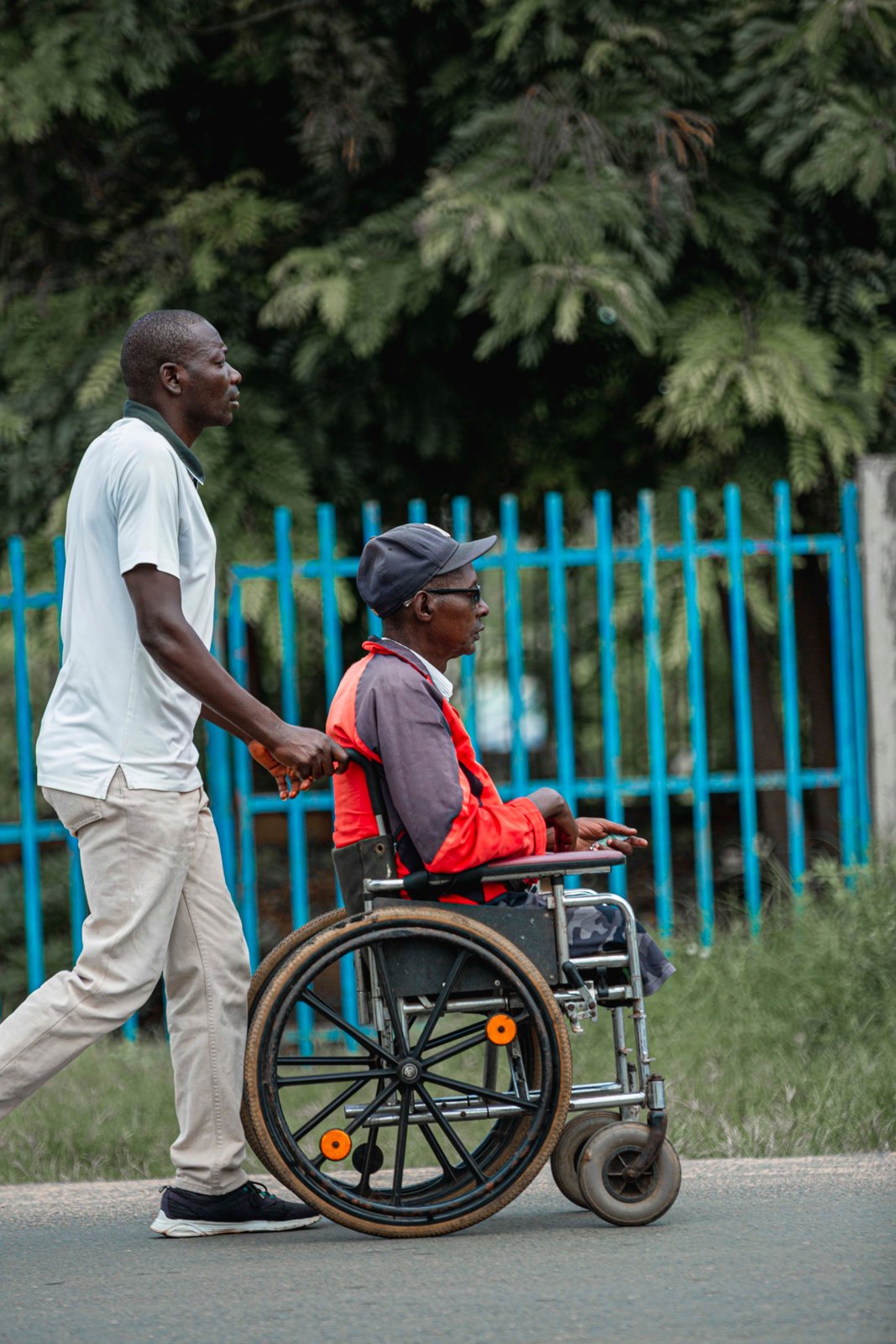 A person supporting a wheelchair user outdoors